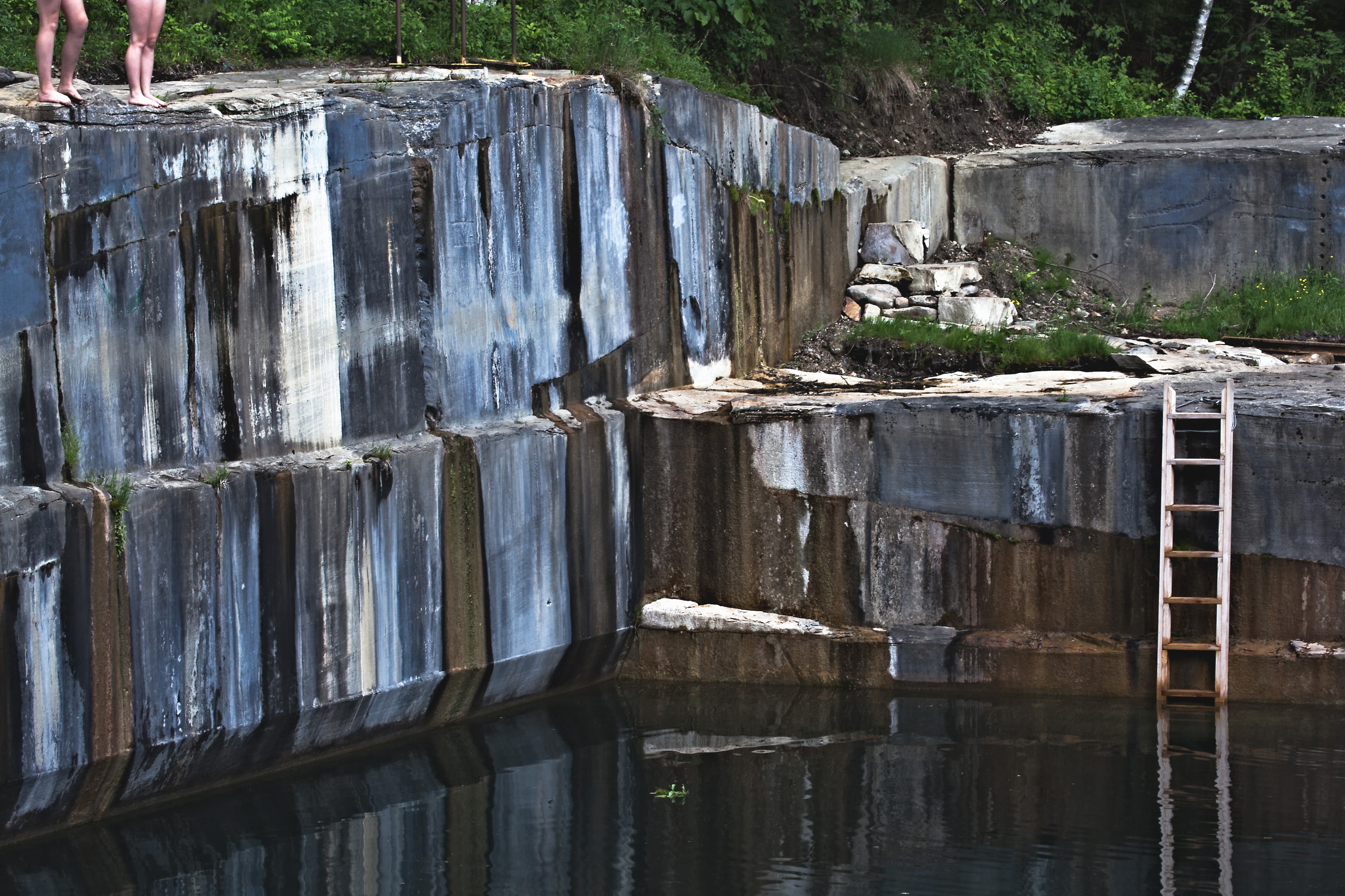Swimmers in clear green water at the flooded Dorset marble quarry swimming hole in Vermont.