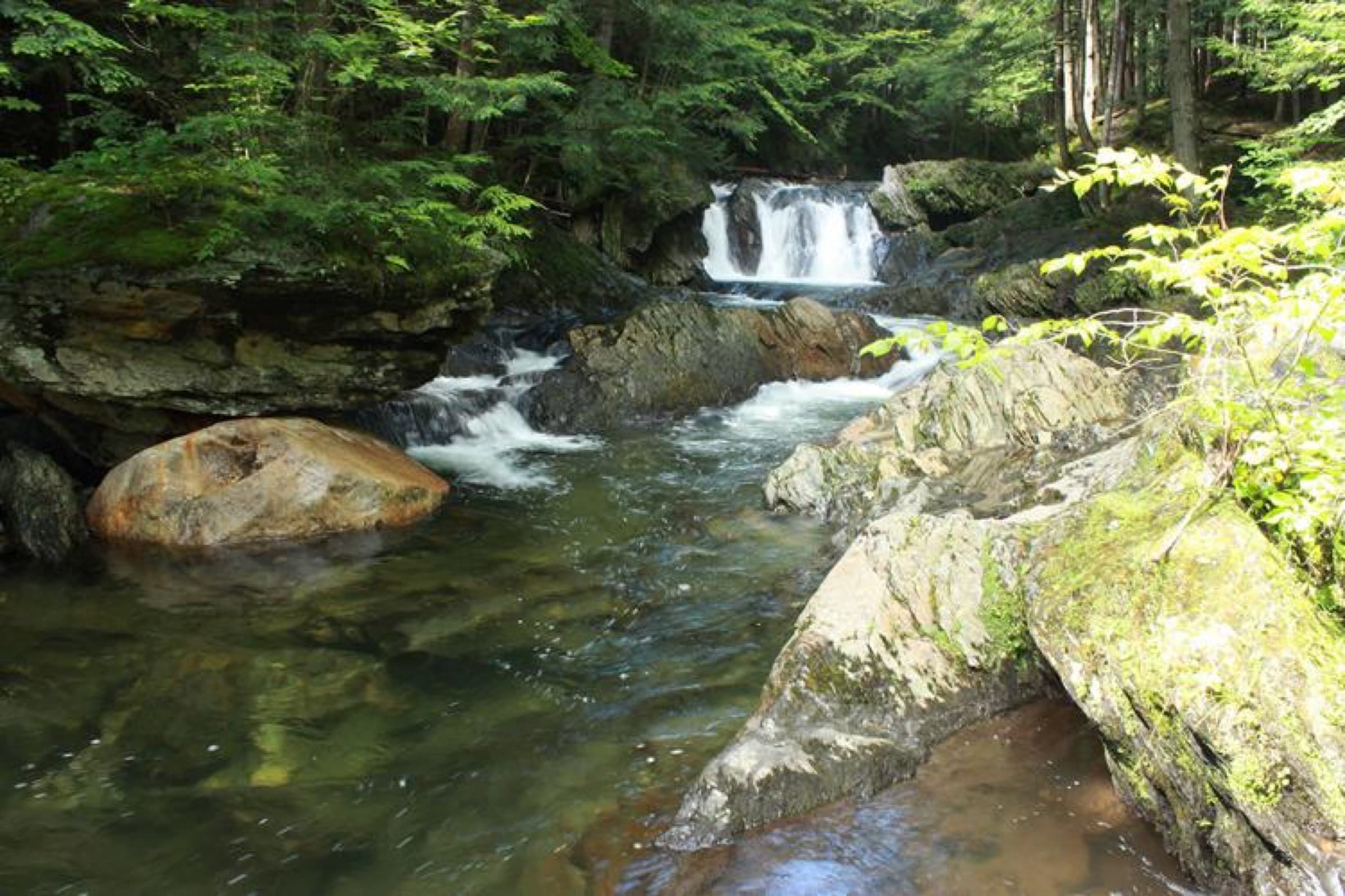 Clear brook pool and small falls at Journey's End Swimming Hole in Johnson, Vermont.