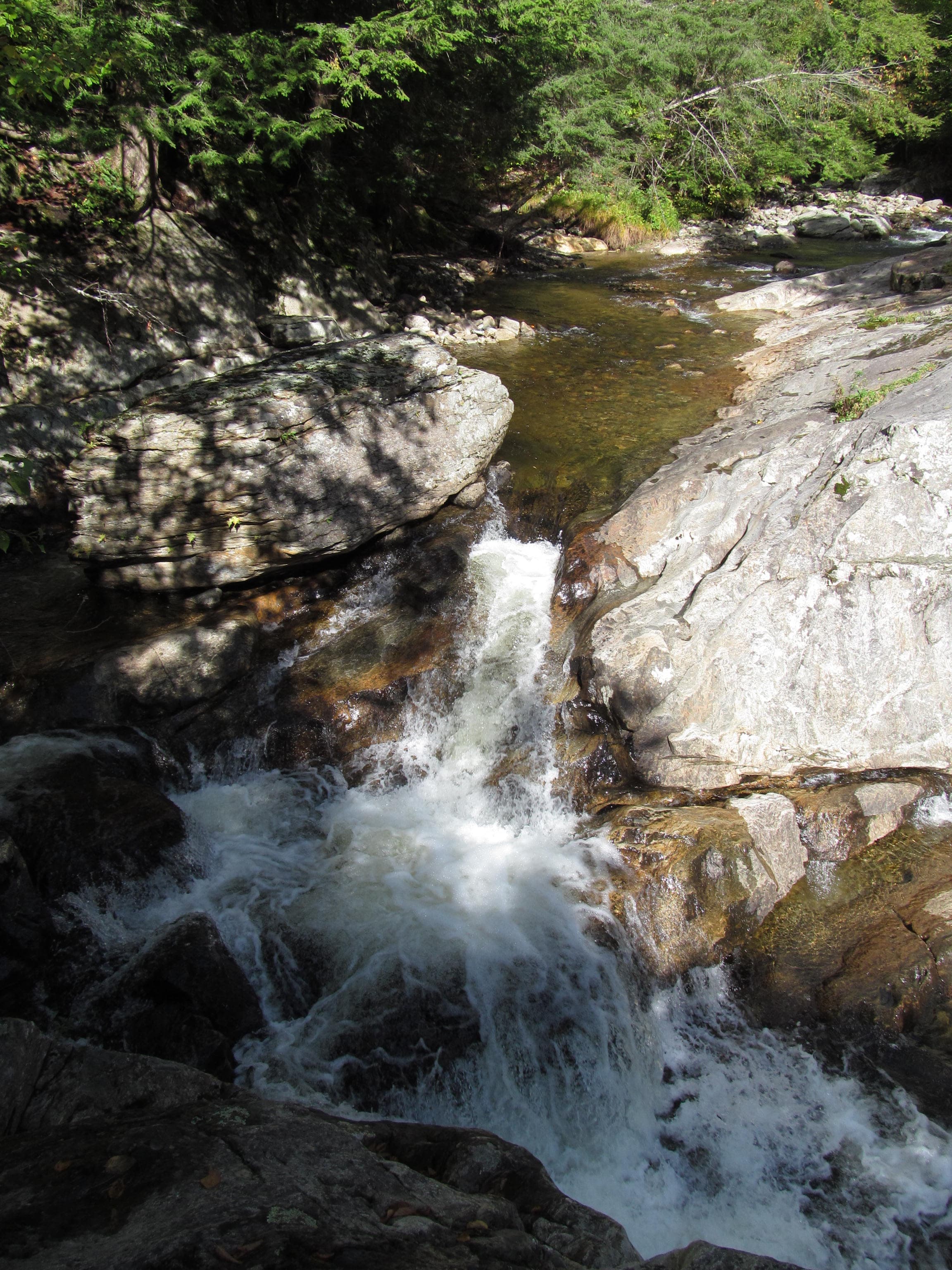 High-angle view of a small falls and clear stream over stone in woods at Buttermilk Falls, Ludlow, Vermont.