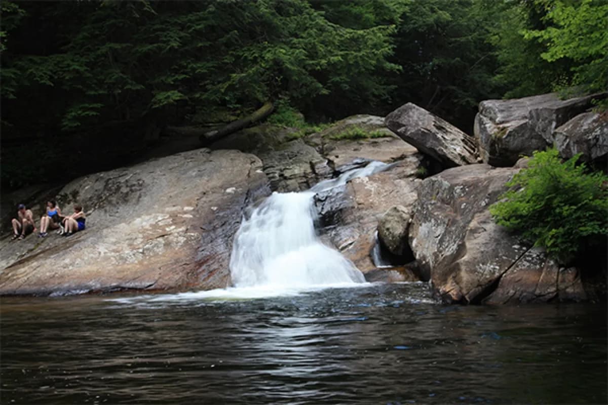 Small New England waterfall spilling into a rocky pool for western Maine trip planning.