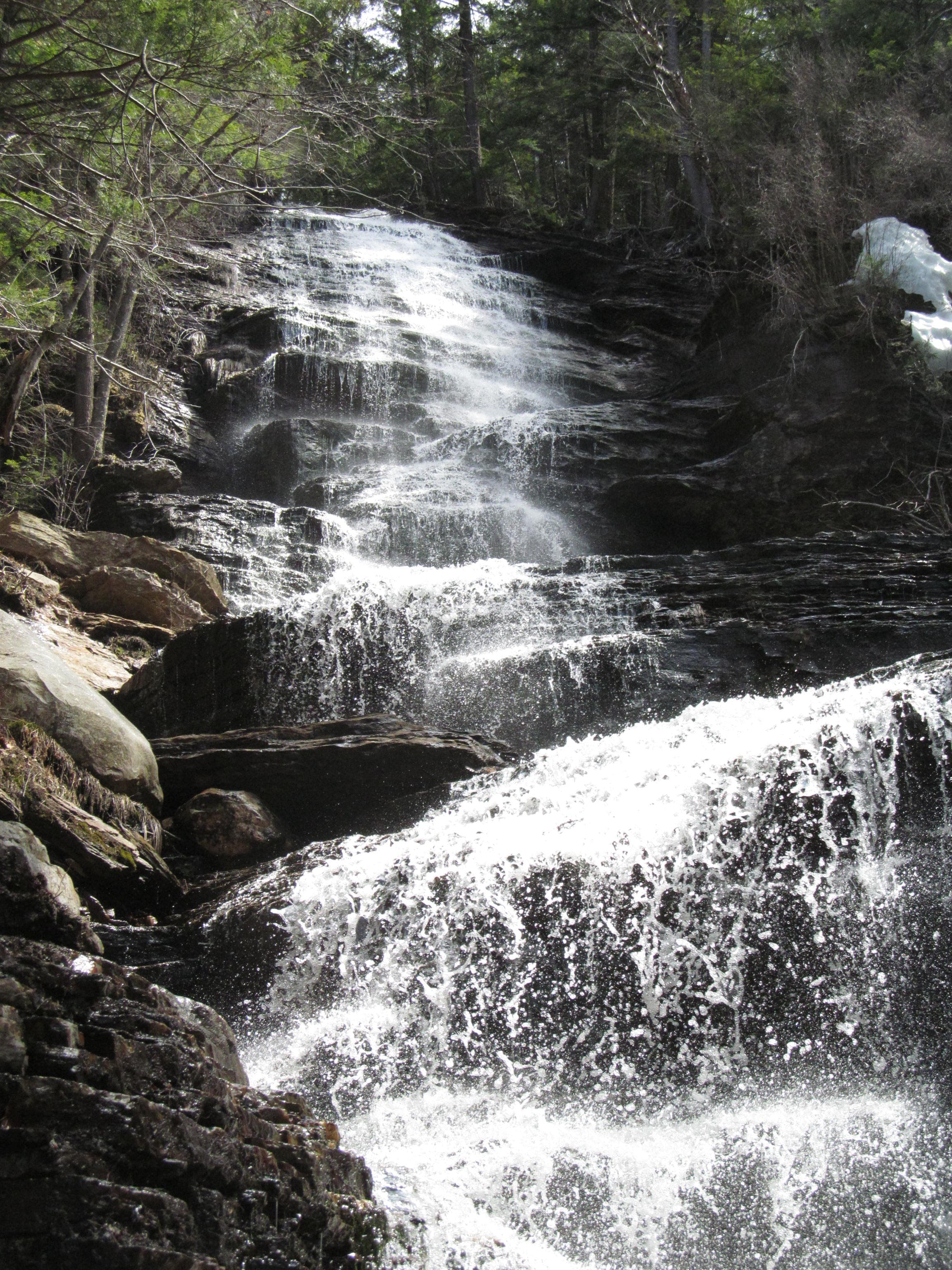 View from beside part of Lye Brook Falls near Manchester, Vermont, with spray, dark rock, and evergreen forest.