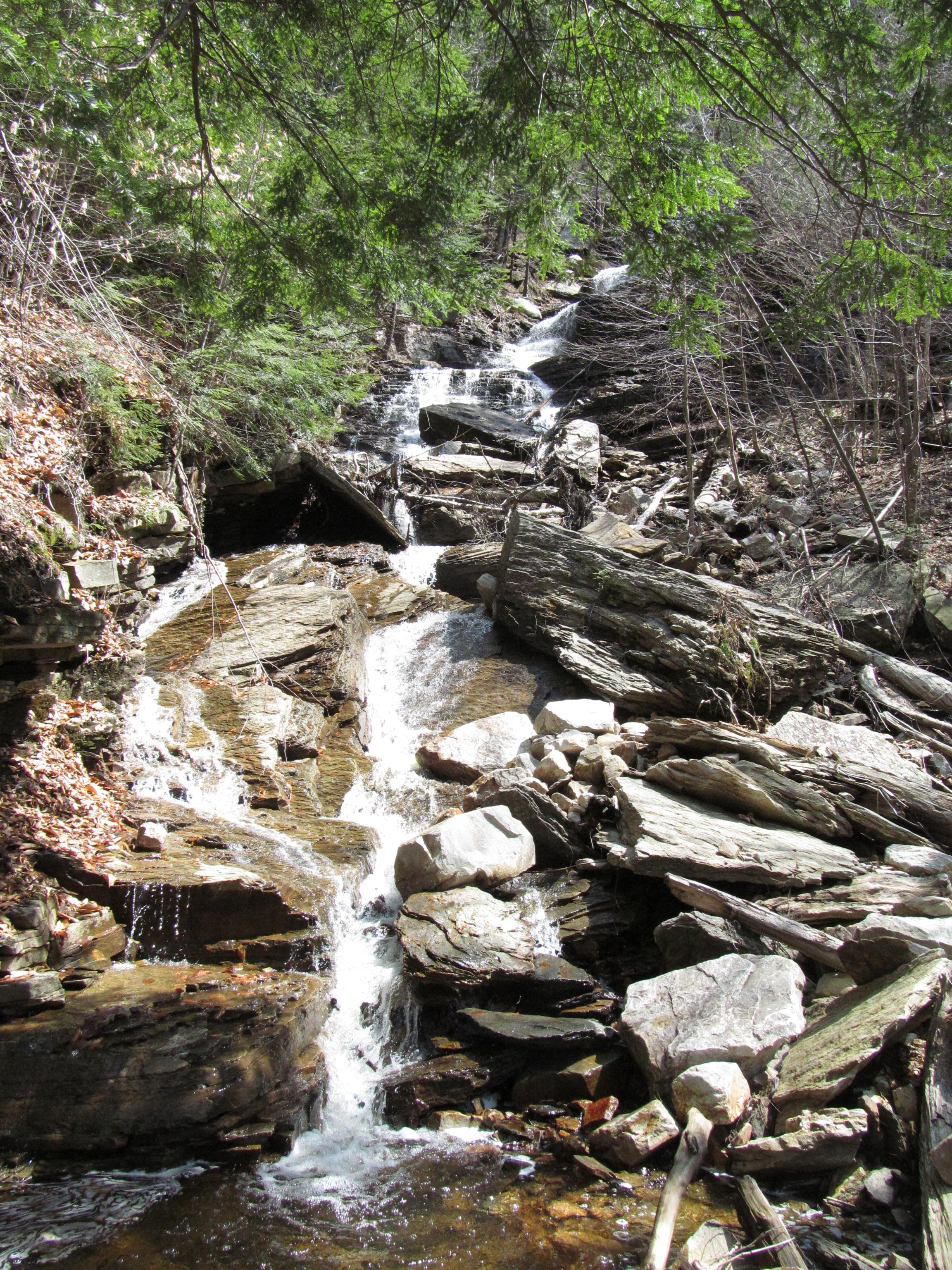 Rocky lower run of Lye Brook Falls near Manchester, Vermont, with water weaving around large boulders and evergreens.