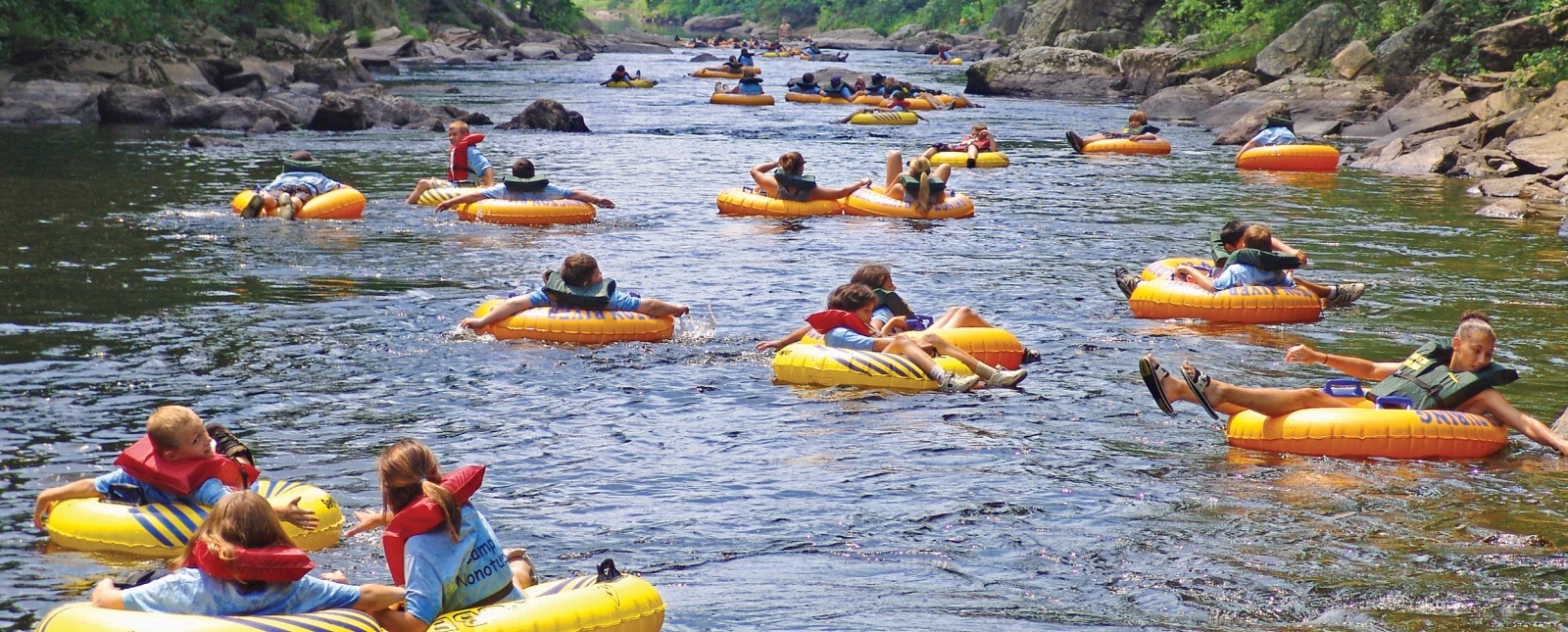 People floating a calm New England river on summer tubes—used for Cape Cod freshwater beach planning.
