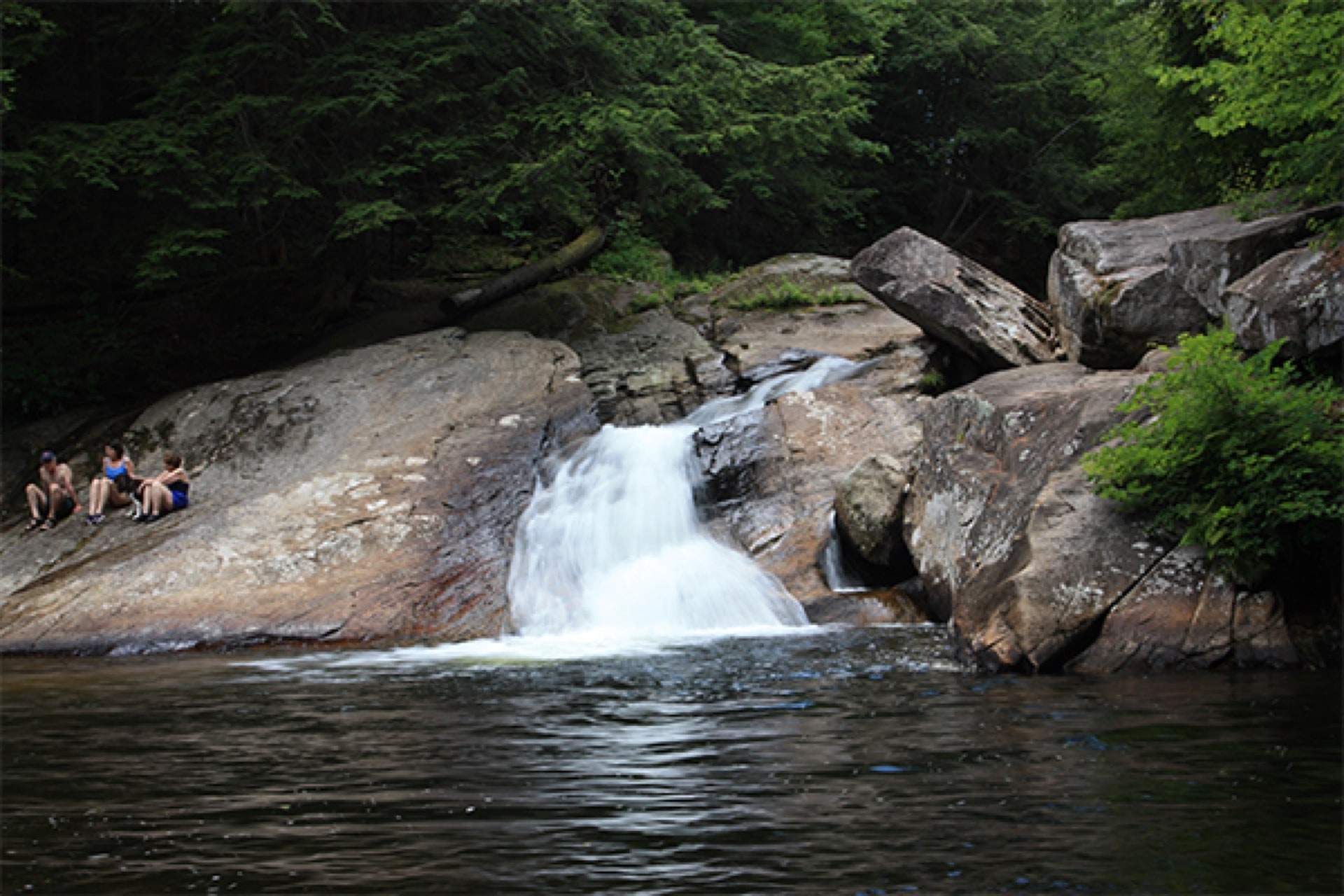 Small New England waterfall spilling into a rocky pool.