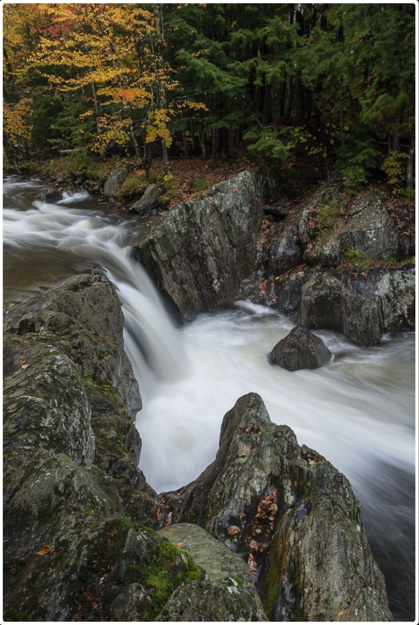 Clear brook pool and waterfall framed by rock at Four Corners Swimming Hole in Troy, Vermont.