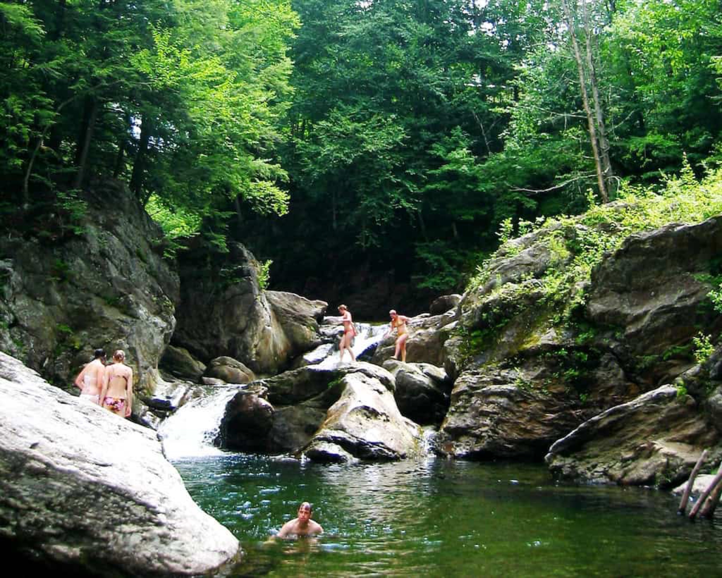 Swimmers and a deep green pool at Trout River Falls, also called Three Holes, in Montgomery, Vermont.
